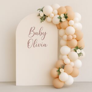 A soft neutral arch backdrop with blush and cream balloon garland, faux florals, and personalised vinyl wording, perfect for smaller or home-based celebrations.