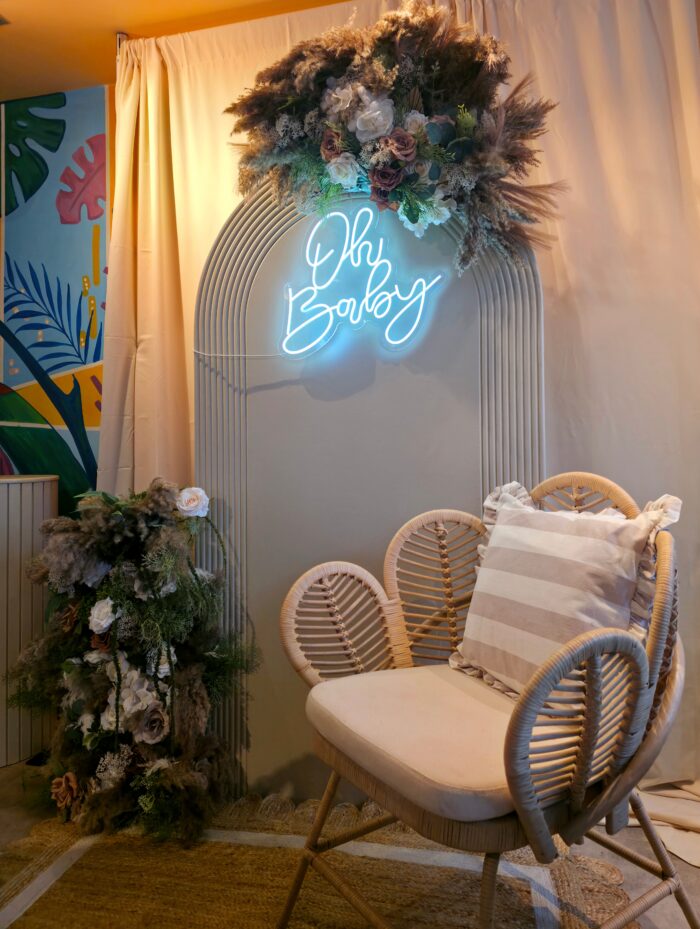 Close-up side angle of Oh Baby neon sign with pampas and rose floral arrangement
