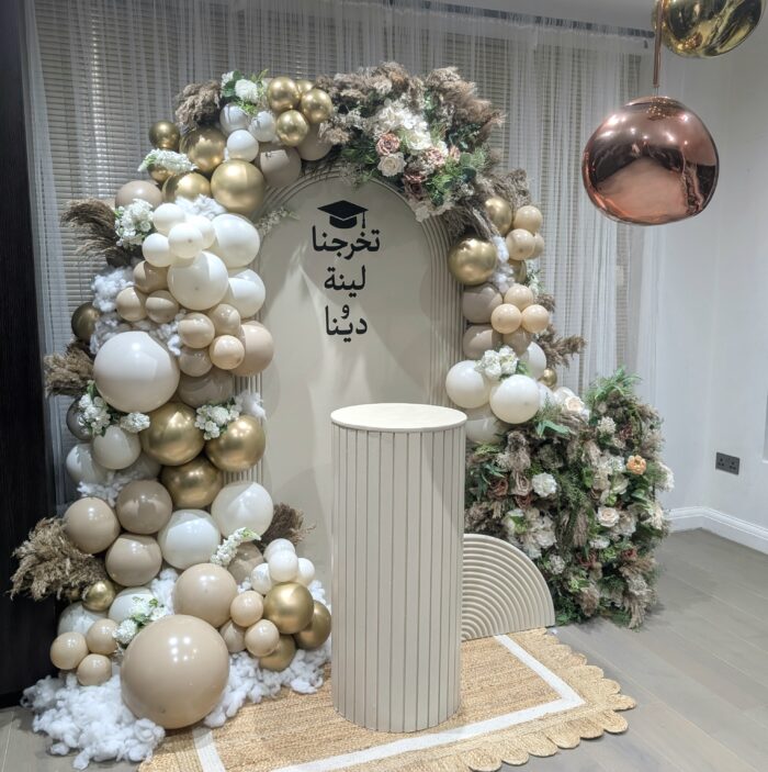 Ribbed plinth, arched backdrop and gold balloon styling for graduation celebration in Harrow