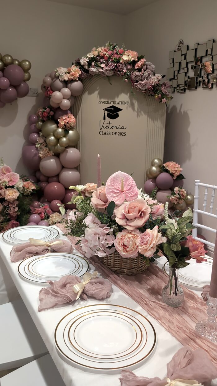 Elegant graduation table decor with gold-rimmed plates, chiffon runner and floral arrangements.