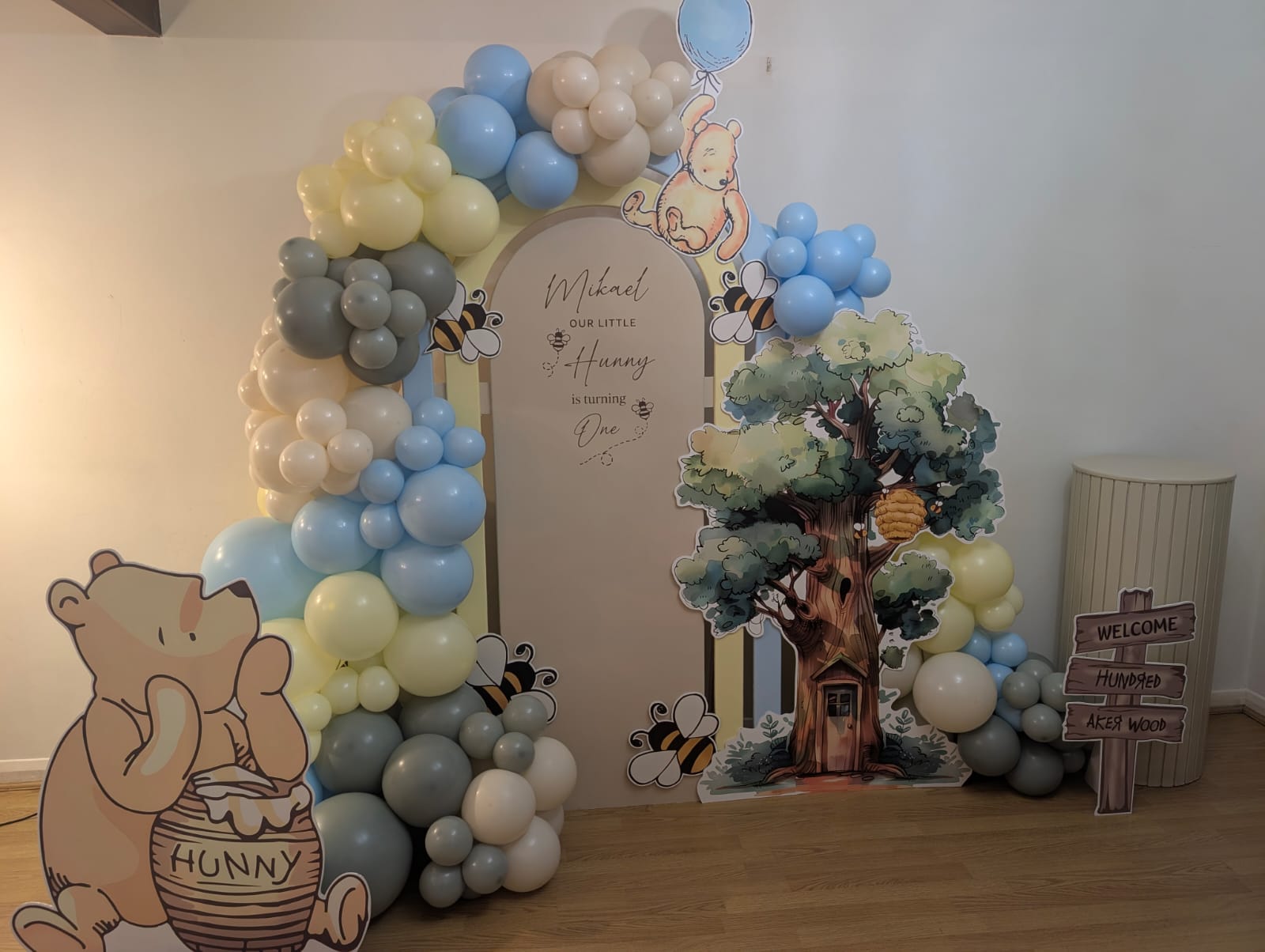 Winnie the Pooh first birthday party decor with personalised arch, balloons and character cut-outs in Slough